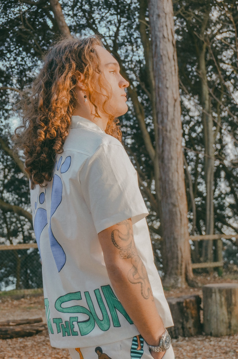 Person wearing a white shirt with colourful graphics in a forest setting